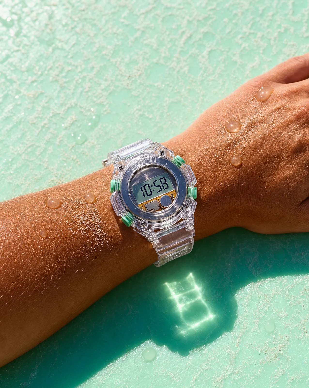The same clear watch on a wet wrist over turquoise water