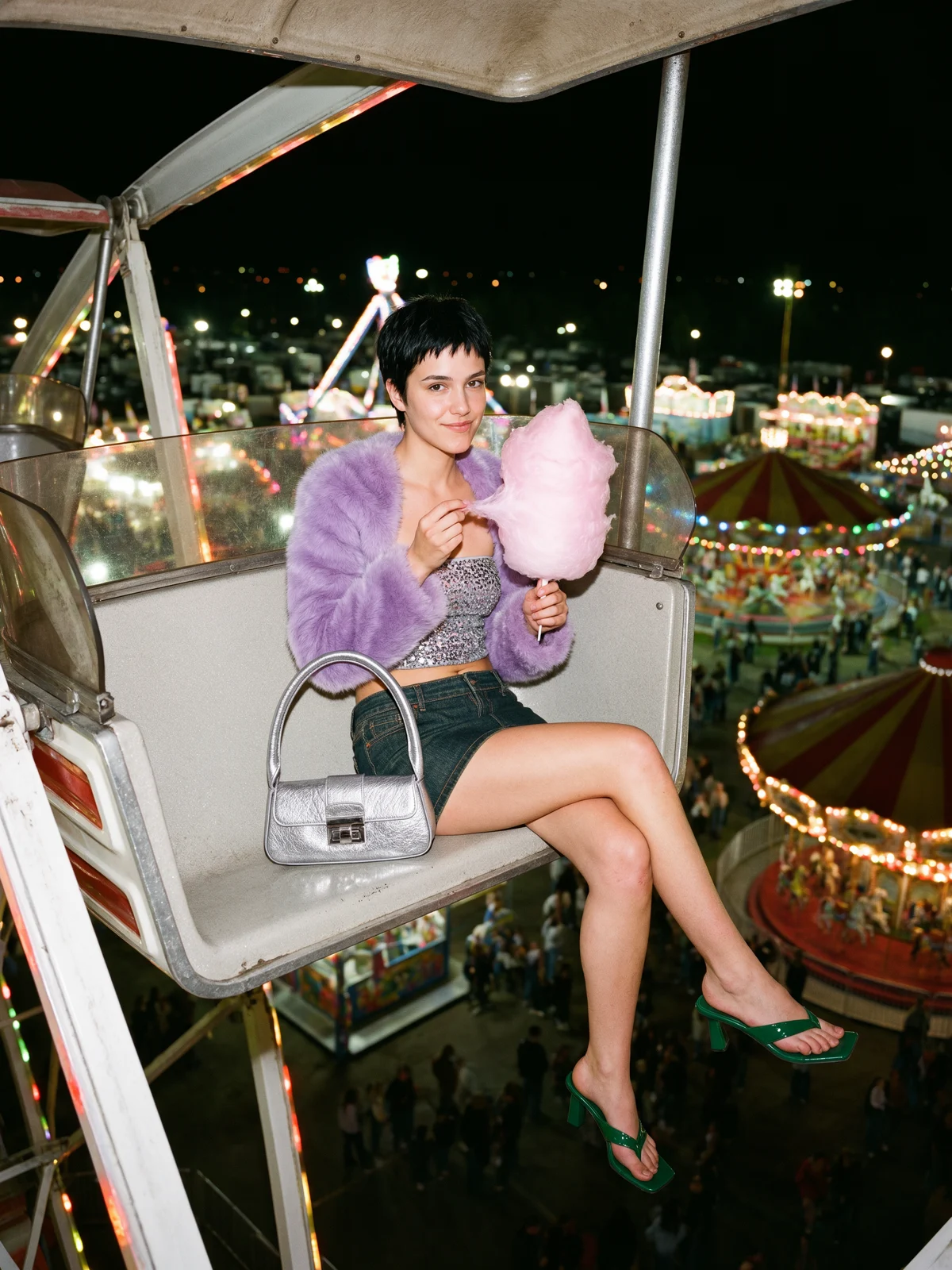 The same woman in a ferris wheel gondola at night