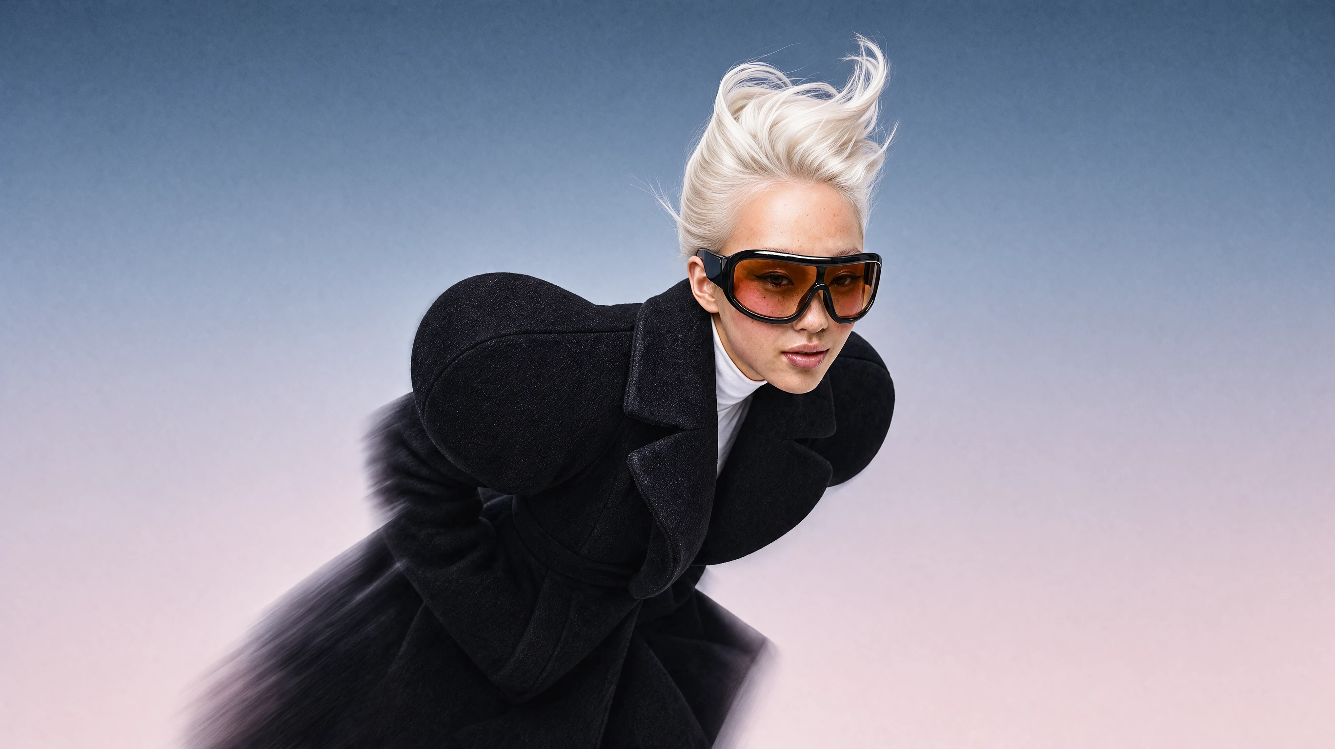 Model with platinum hair and orange sunglasses in a black wind coat