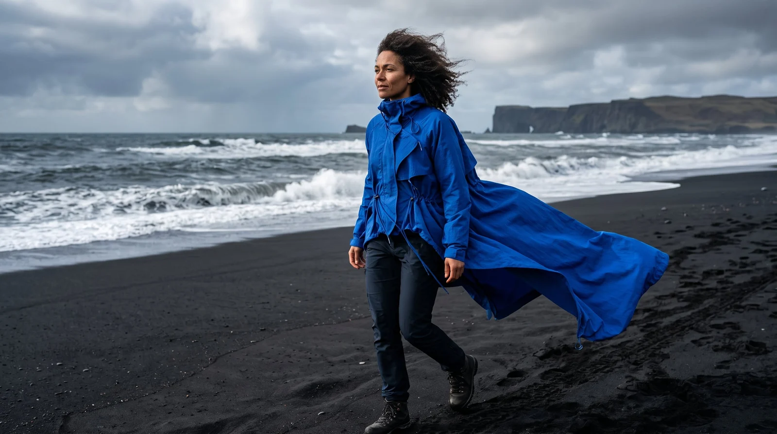 Fashion image of a woman in a cobalt jacket on a volcanic beach
